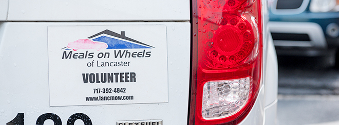 Meals on wheels of Lancaster volunteer car sticker on back of white car