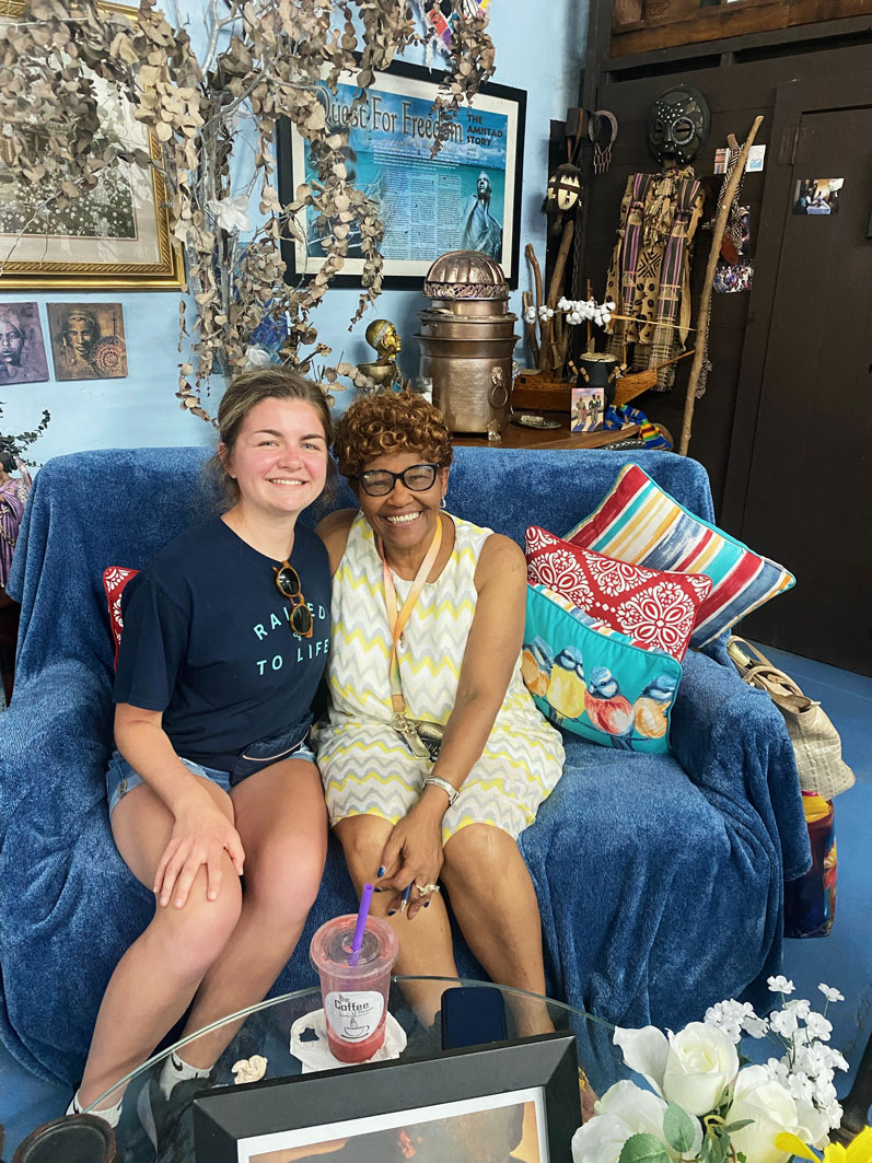 Two women sitting on a couch, smiling, posing for a photo