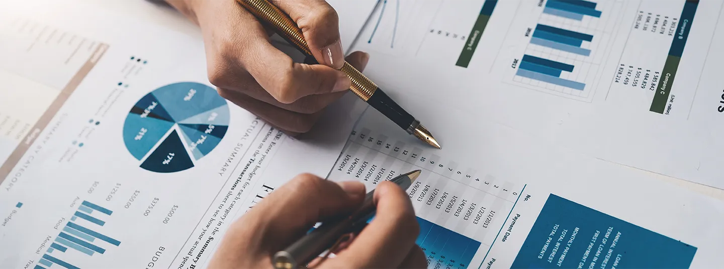 Two hands pointing to and review financial charts.