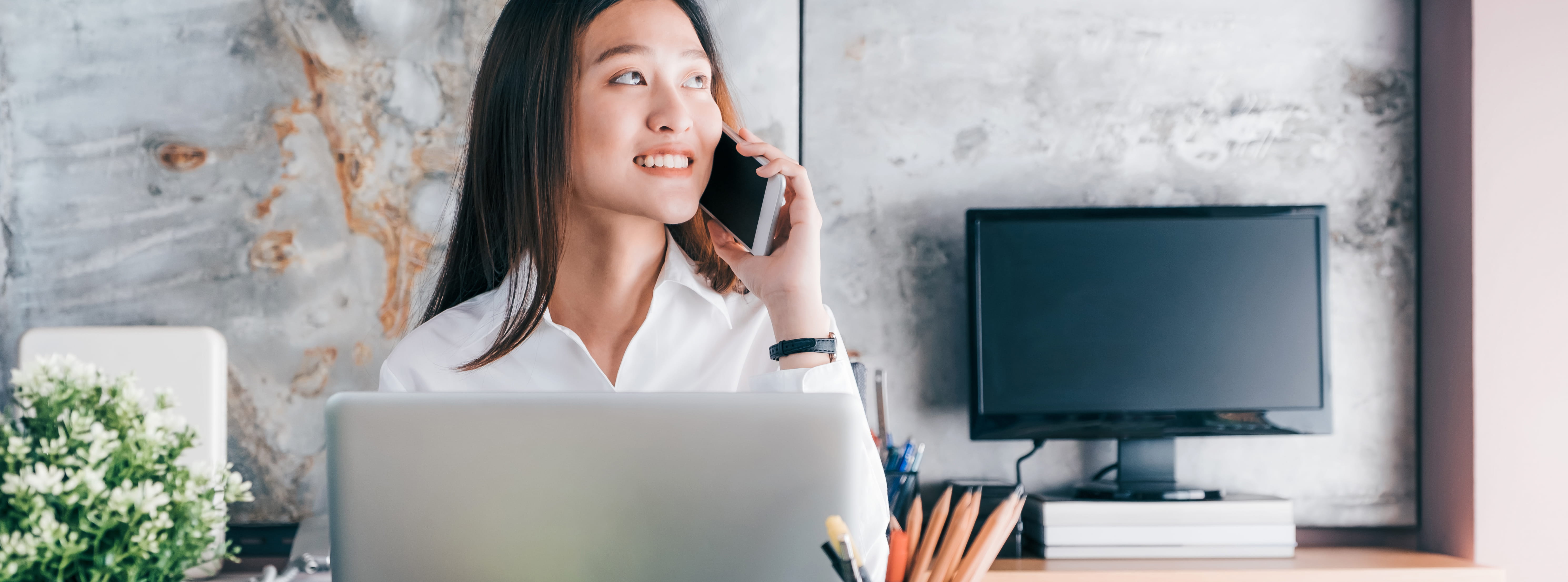 Asian professional woman smiling while on the phone in an office