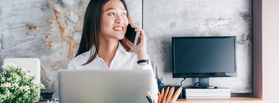 Asian professional woman smiling while on the phone in an office