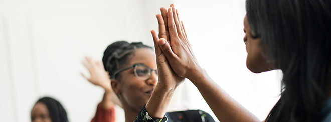 Two women giving each other high fives for teamwork