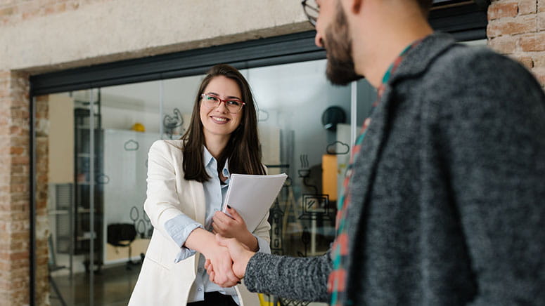 Young woman and young man share firm handshake and smile