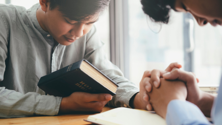 Asian men praying with bibles