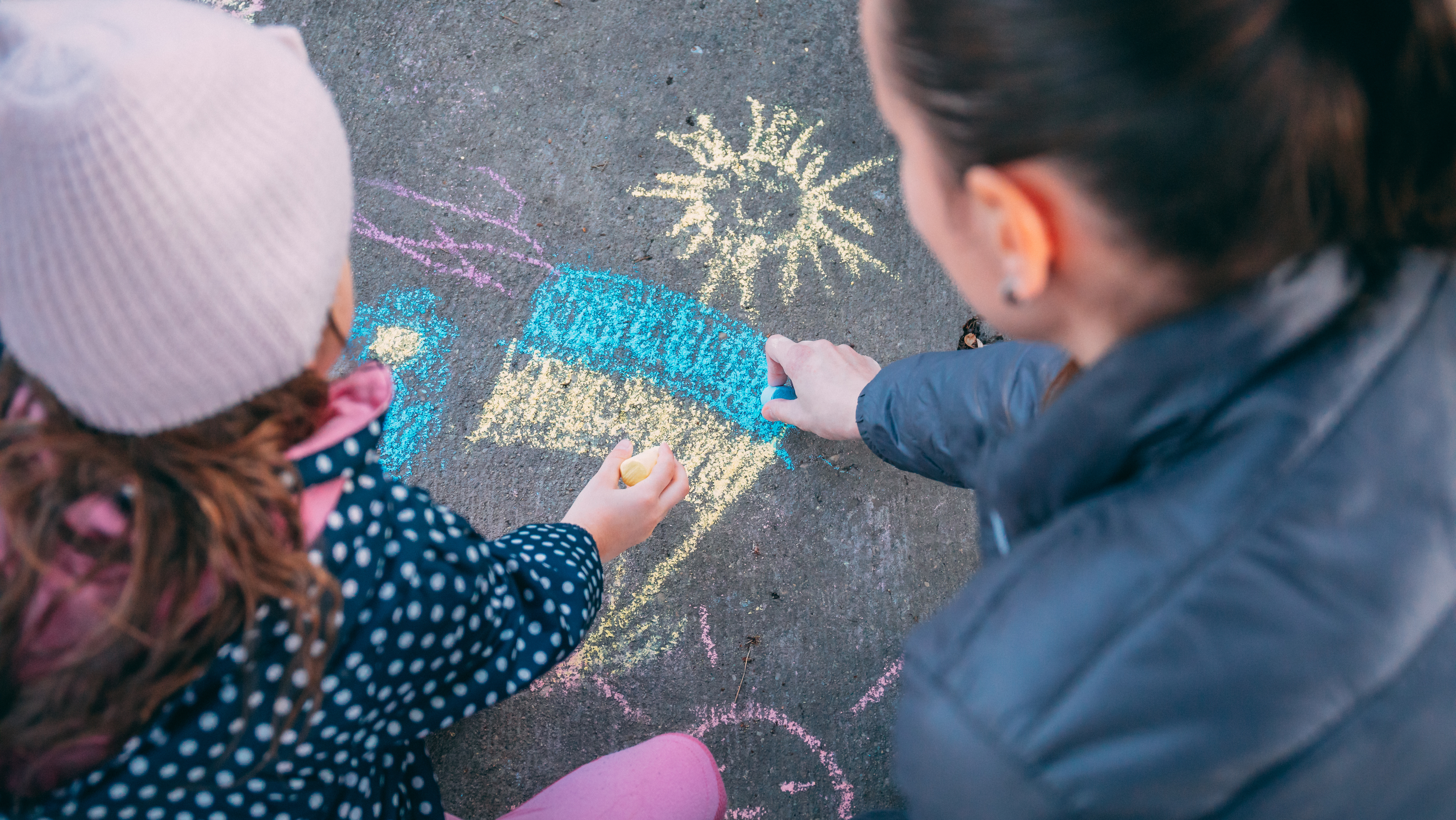 Mother and daughter draw Ukrainian flag with sidewalk chalk