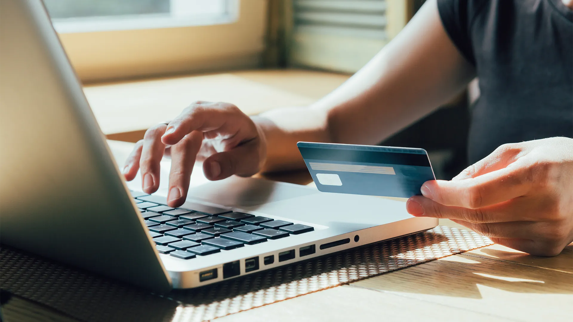 Credit card being held by woman typing on the laptop computer.