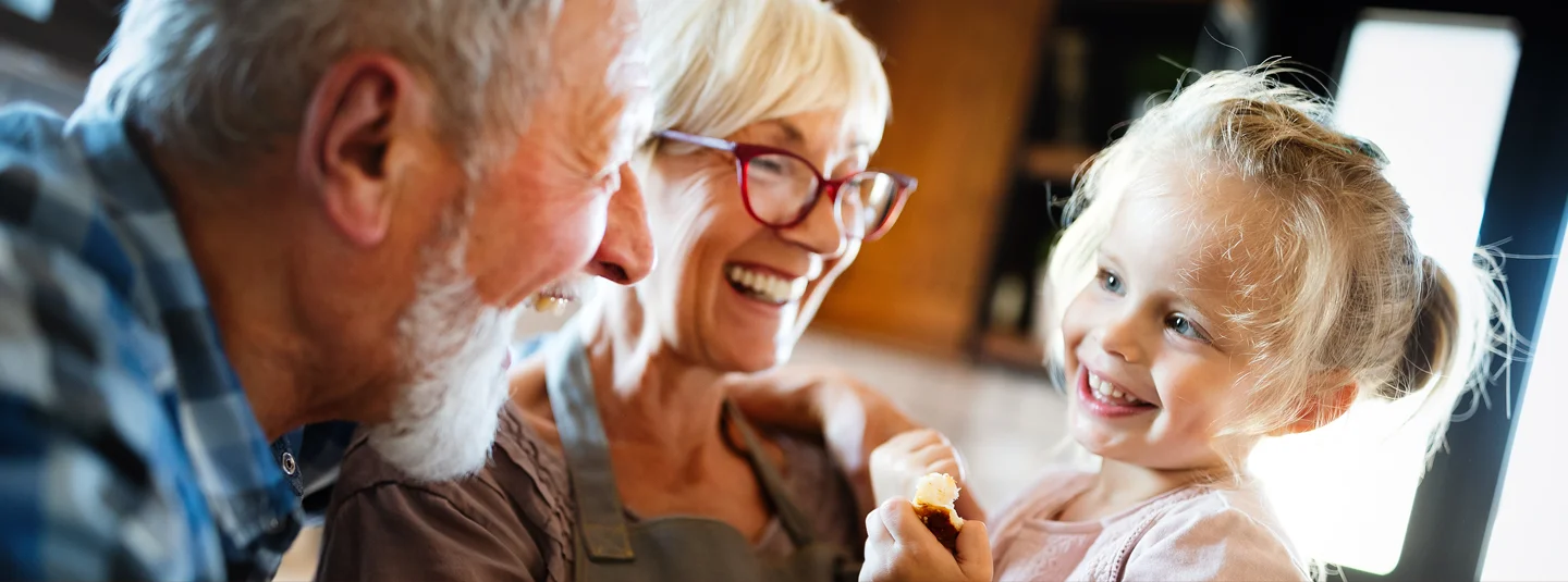 Grandma and Grandpa holding their granddaughter and laughing
