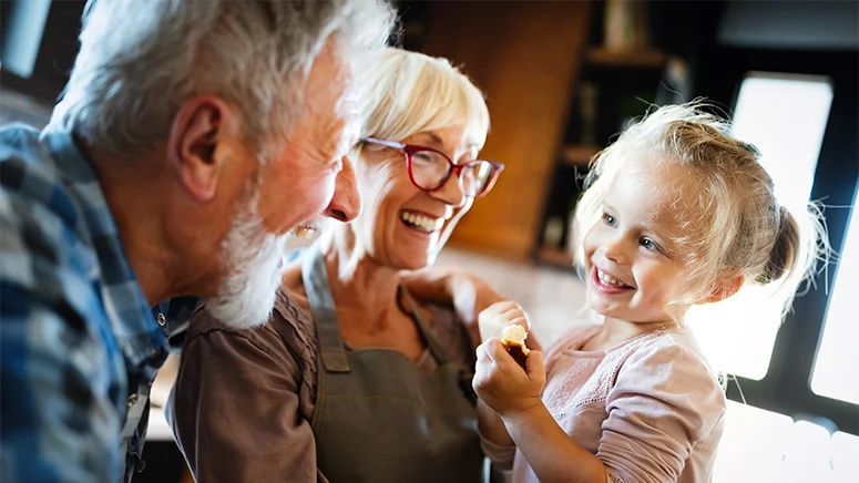 Grandma and Grandpa holding their granddaughter and laughing