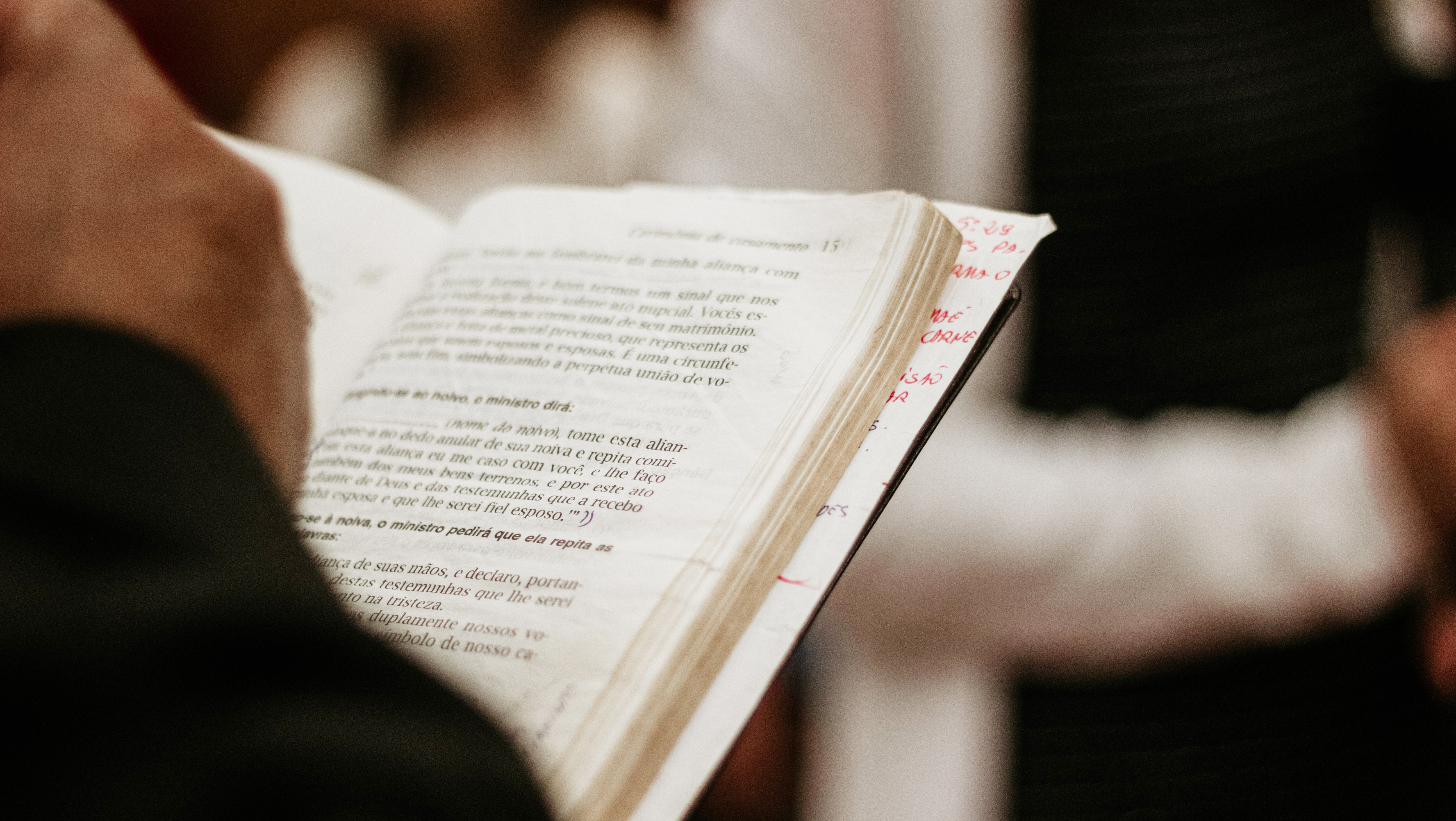 Closeup of pastor reading Spanish-language Bible during worship. Photo by Nicolas Rizzon on Unsplash.