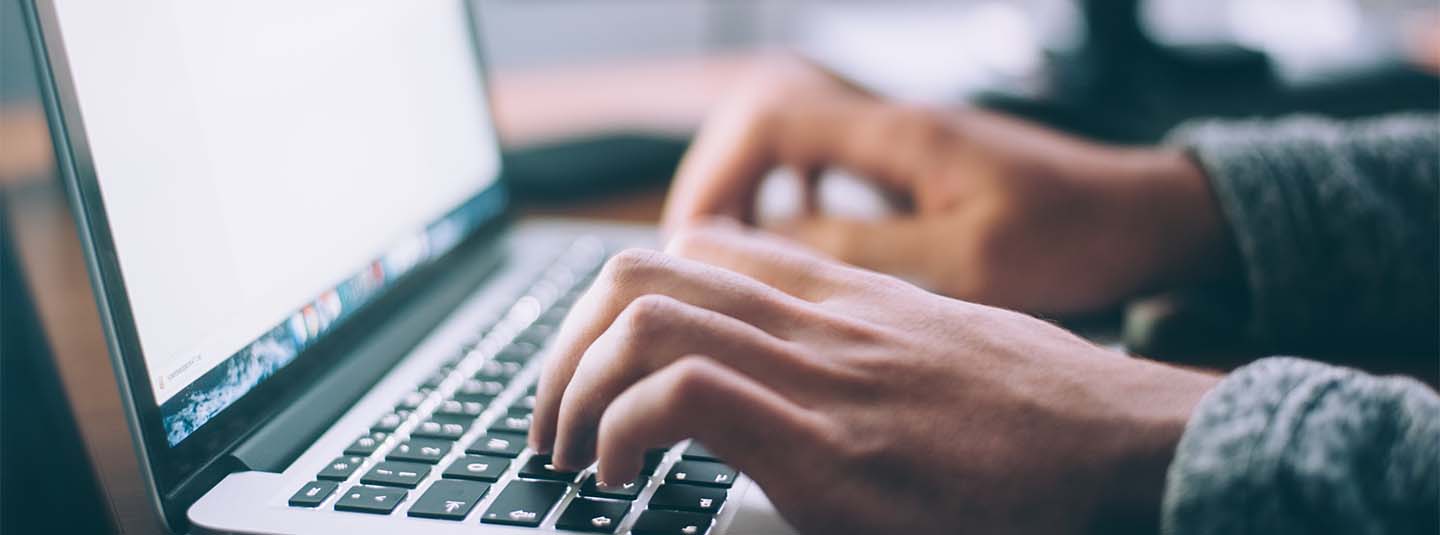 Hands on laptop keyboard with bright laptop screen behind