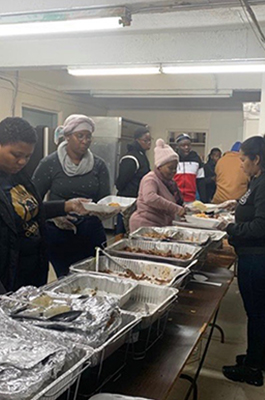 Members and community around church of Evangelical Garifuna Church of Manhattan at Thanksgiving meal buffet line 2019