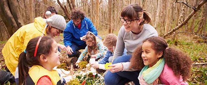 Group of kids enjoying an activity in a forrest lead by volunteers