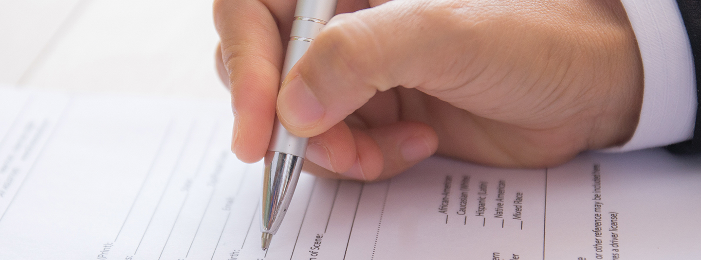 Close up of a hand filling out a form with a pen