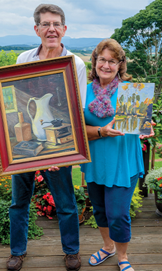 Couple holding two different framed art pieces 