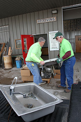 Two men helping each other lift a sink