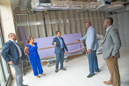 Kevin Gil, Randy Nyce, Bryant Keel, Leonard Dow and Natalie Martinez stand in circle talking inside construction for new Everence office in Philly