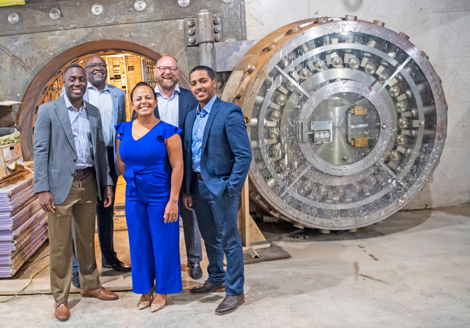 Kevin Gil, Randy Nyce, Bryant Keel, Leonard Dow and Natalie Martinez stand smiling in front of vault of new Everence Philly building under construction