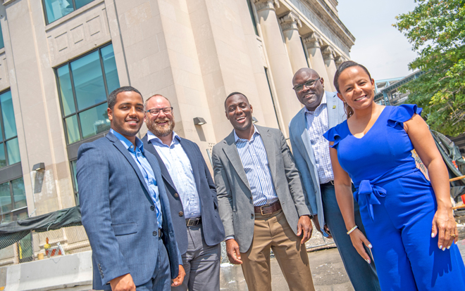 Kevin Gil, Randy Nyce, Bryant Keel, Leonard Dow and Natalie Martinez stand smiling in front of new Everence building in Philly