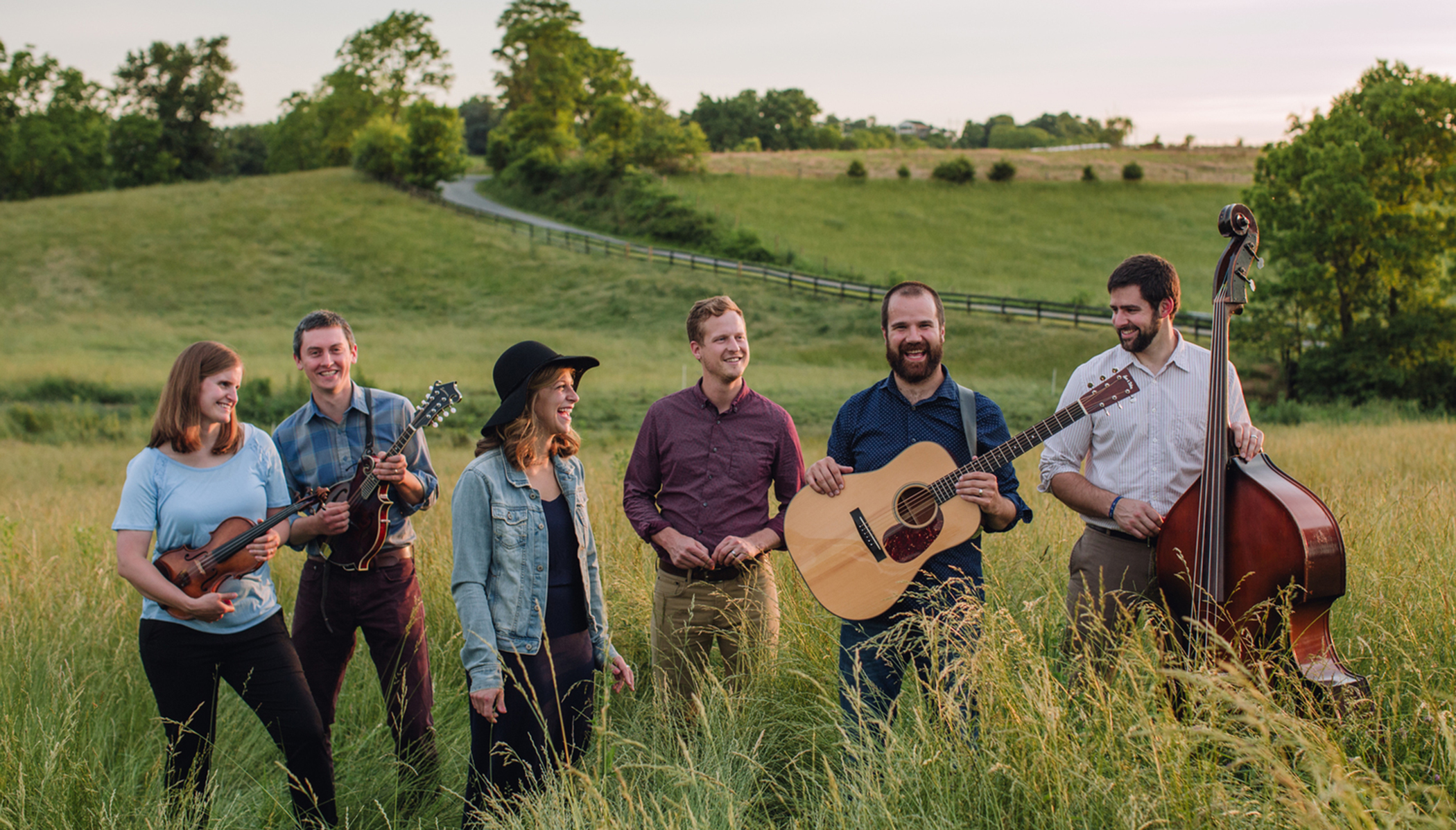 Band gathered for a photo shoot with their instruments in a field.