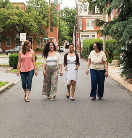 Bridge of Hope women walking down street laughing and talking with trees and buildings behind in background