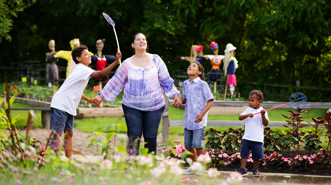 Mother with three children playing outdoors with butterfly nets