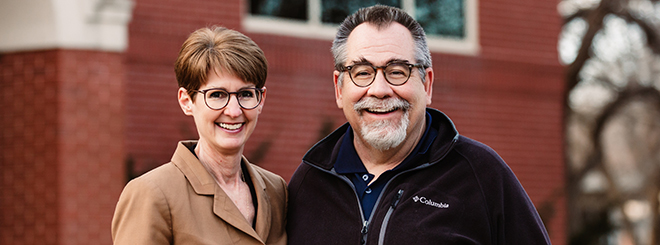 Couple smile in front of church.