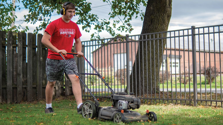 A 15-year-old boy mows grass