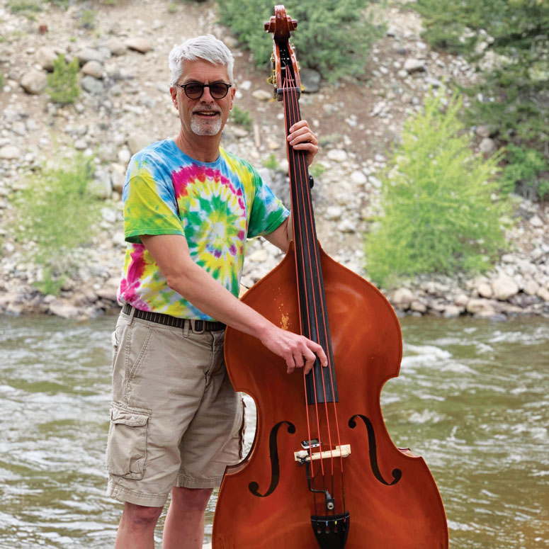 A man poses for a photo while holding a double bass