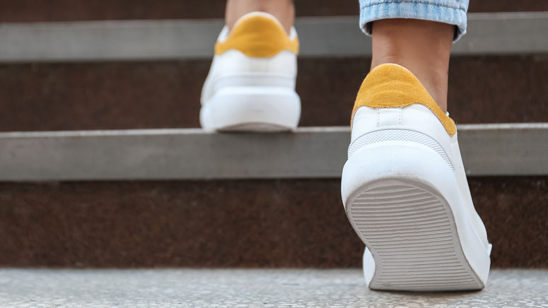 A close up on the back of someone wearing sneakers walking up stairs