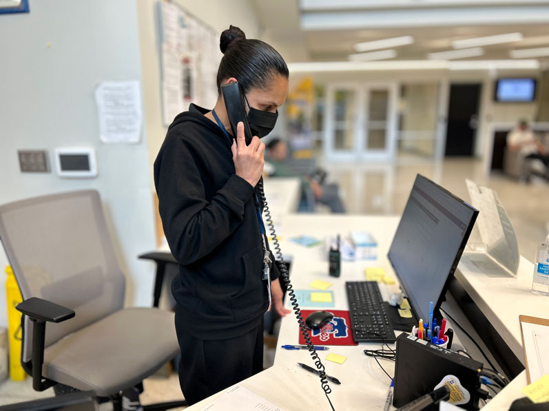 A woman stands at a desk, talking on the phone