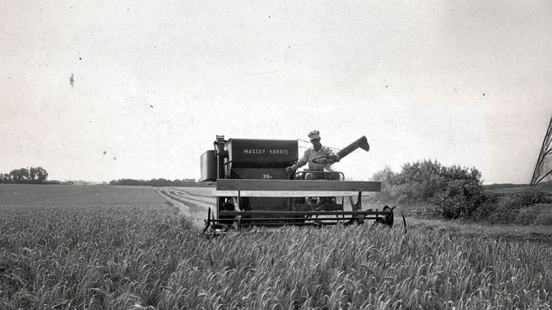 A farmer riding on farming equipment, working the field