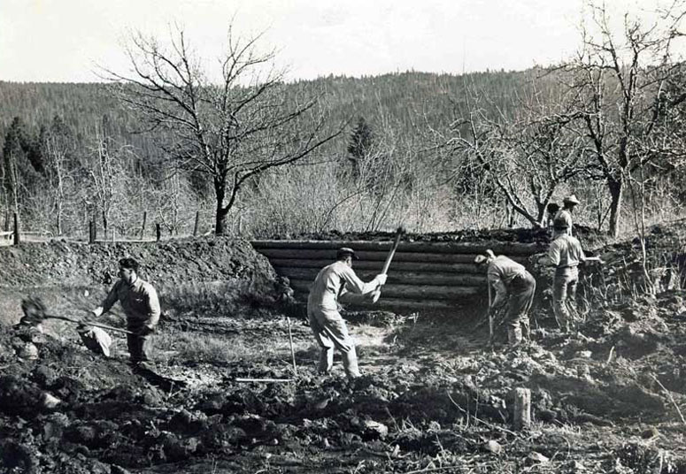 A black-and-white photo taken in the 1940s showing men building a dam