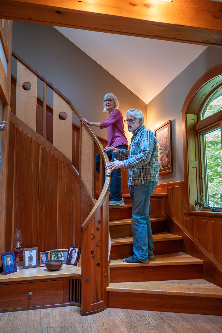 A couple stands on custom-built wooden stairs in its home