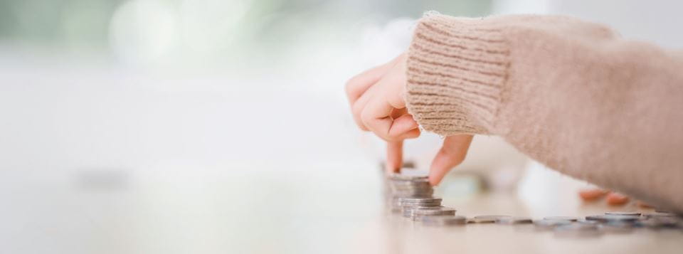 A small hand stacks coins on a surface