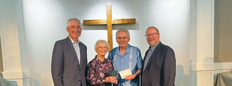 A group of people, three men and a woman, stand posing for a photo inside a church