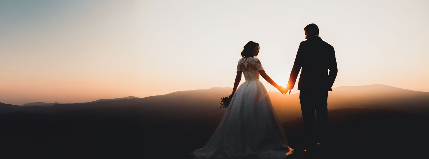 A newly wed husband and wife hold hands looking at each other