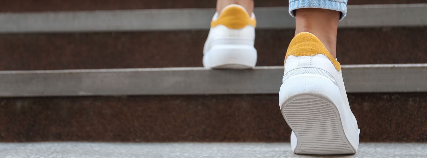 A person wearing sneakers walking up some steps