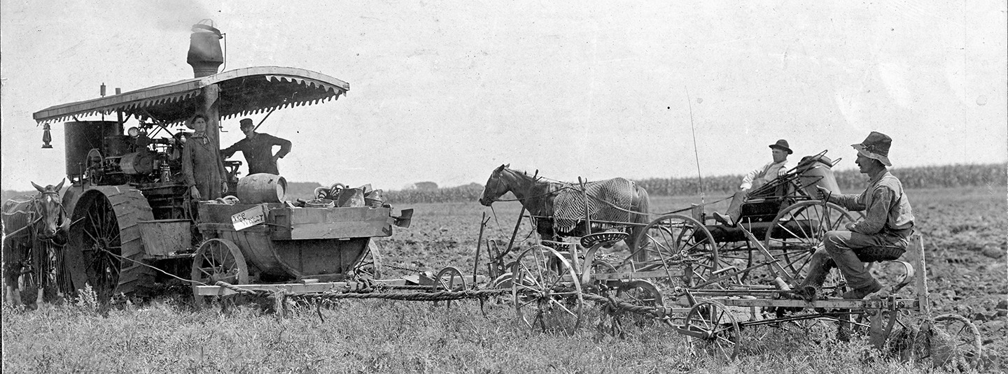 Black and white photo of men in a wheat field with horses and a tractor
