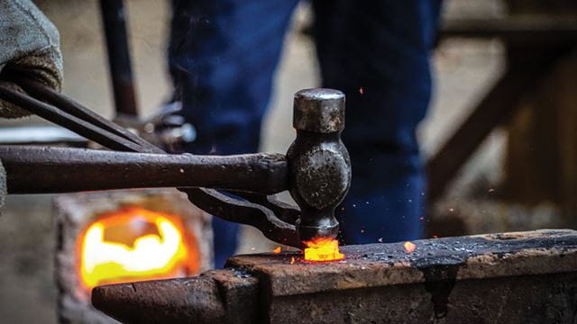 Forging with a hammer on a fire.