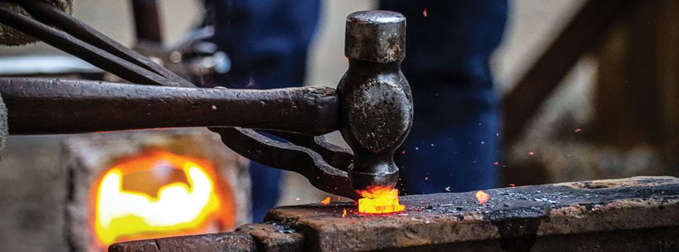 Forging with a hammer on a fire.