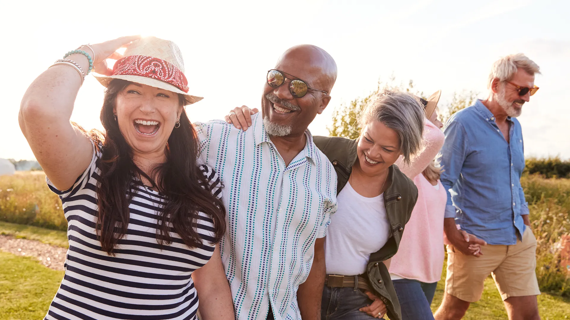 A group of multi-racial middle-aged people walk outside in golden hour light.