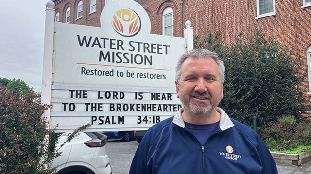 Jack Crawly of Water Street Mission posing in front of sign.