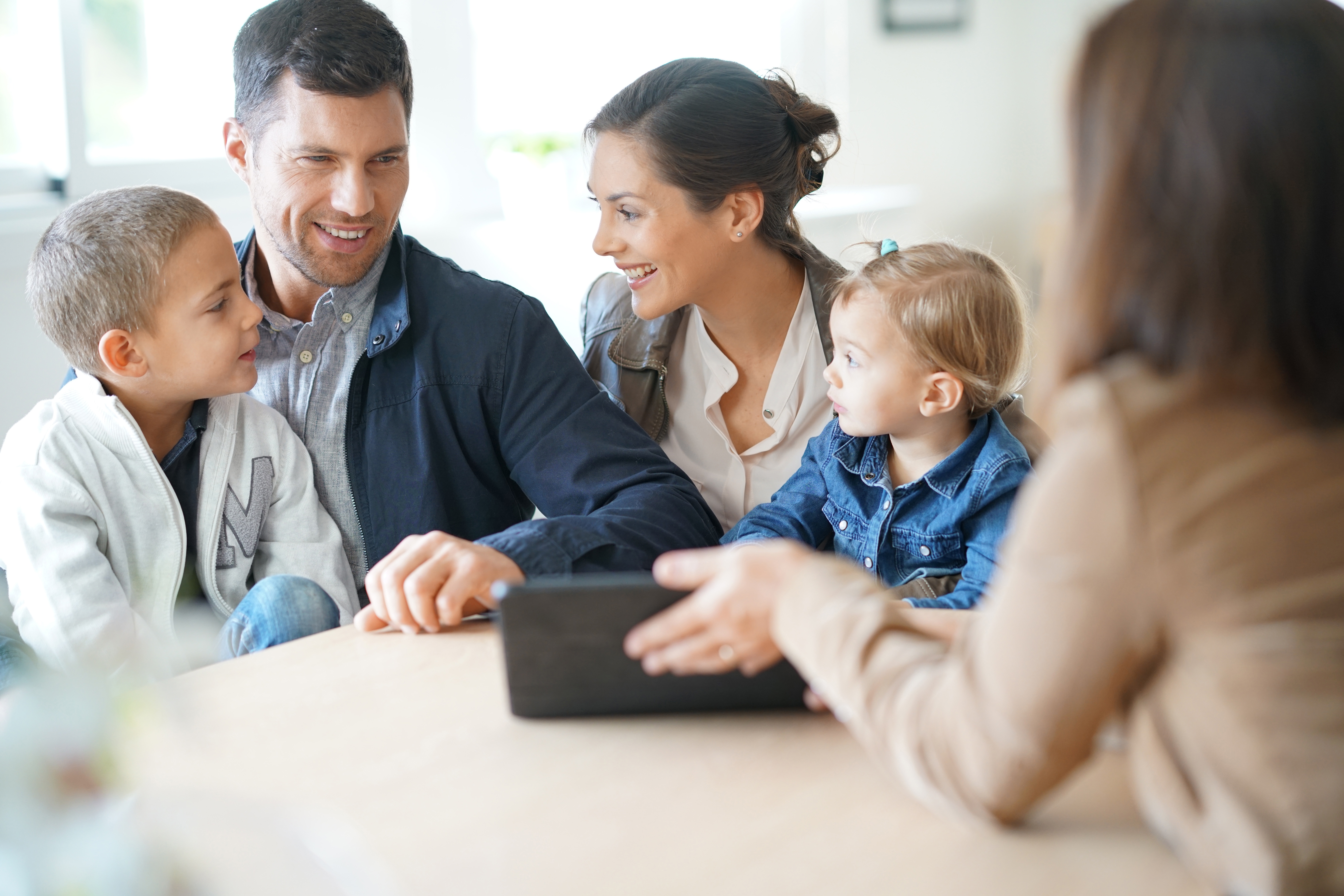 White family of four look at an ipad over a table with a professional woman.