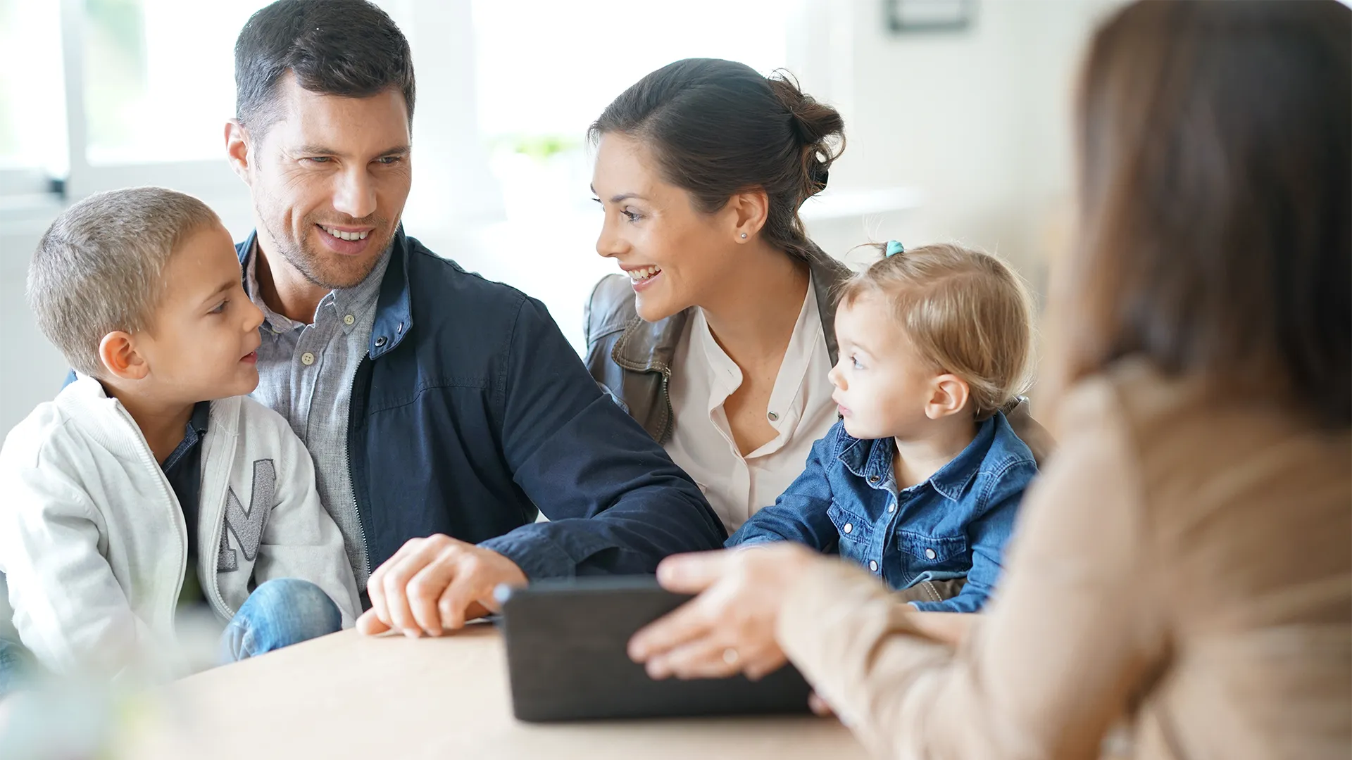 White family of four look at an ipad over a table with a professional woman.
