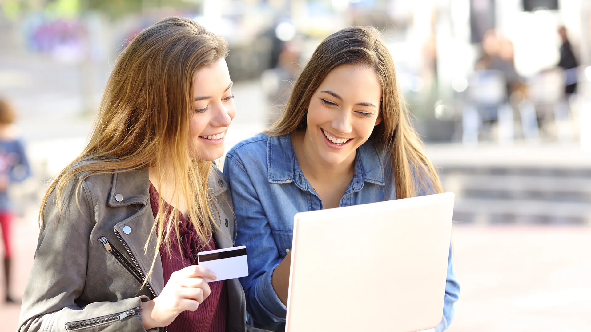 Two women smiling while looking at a screen and holding a credit card.