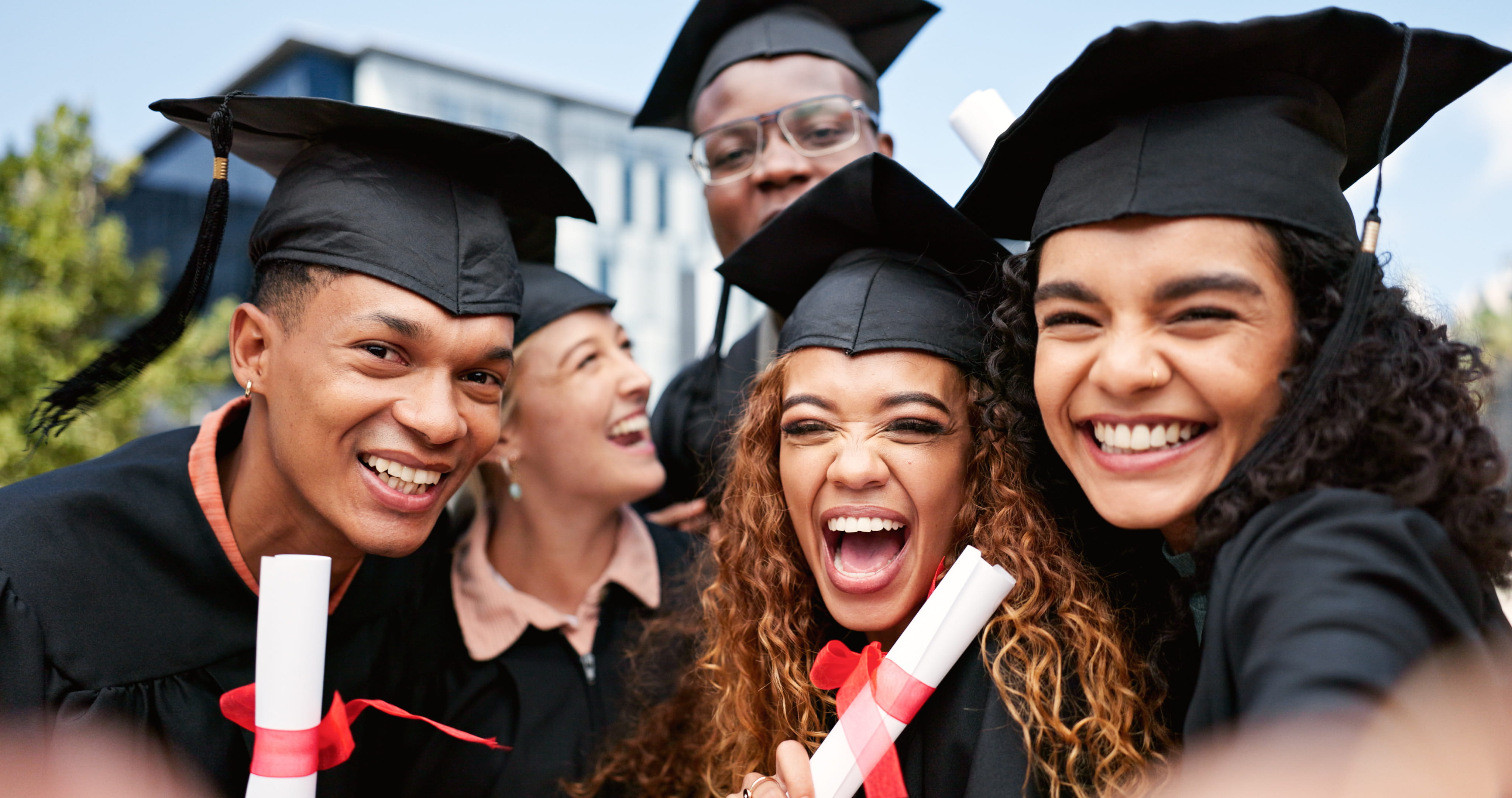 A group of college graduates smiling and celebrating in their cap and gowns