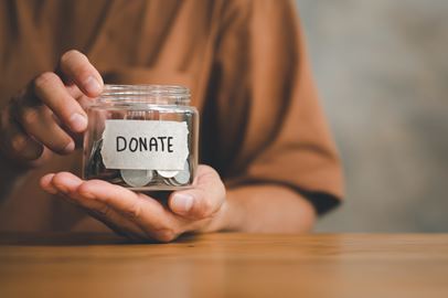 Man holding money jar with DONATE word written text label for giving and donation.