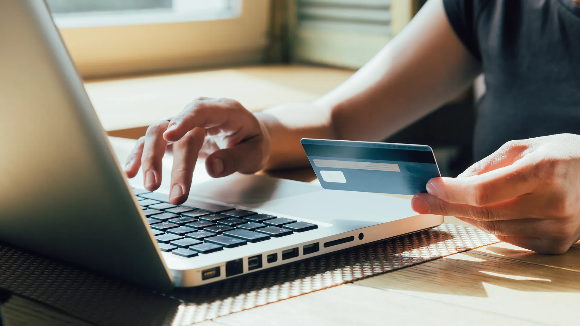 Woman with credit card in her hand typing on a computer.