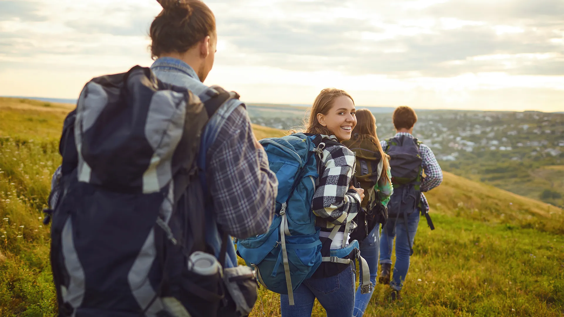 A group of individuals wearing backpacks and walking down a hill.