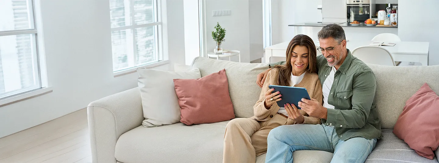 A couple sitting on the couch looking at an iPad.
